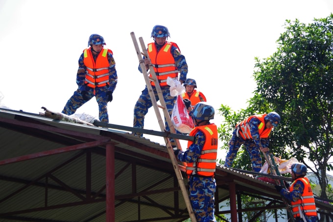 Cán bộ, chiến sĩ Lữ đoàn 170 giúp dân đặt bao cát lên mái nhà chống bão. Ảnh: Đoàn Hiệp
