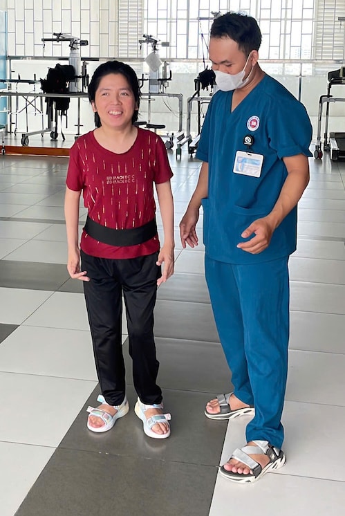 Linh đi lại tại Bệnh viện 1A, bên cạnh cử nhân vật lý trị liệu Danh Huỳnh Minh Tâm. Ảnh: Lê Phương