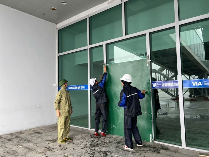 Nhân viên cảng hàng không Phú Bài che chắn cửa kính trước khi bão Bualoi đổ bộ. Ảnh: ACV
