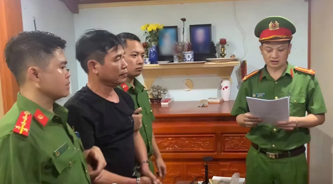 Ông Cường (mặc áo đen), nghe cảnh sát đọc lệnh bắt. Ảnh: Công an cung cấp