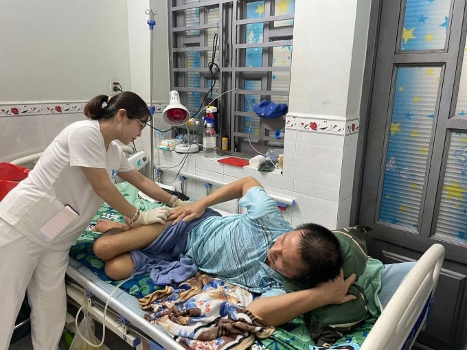 Chị Phạm Thị Xuân xem vết thương cho ông Nguyễn Văn Thương ở phường Bình Hưng Hòa, TP HCM, chiều 24/9. Ảnh: Ngọc Ngân