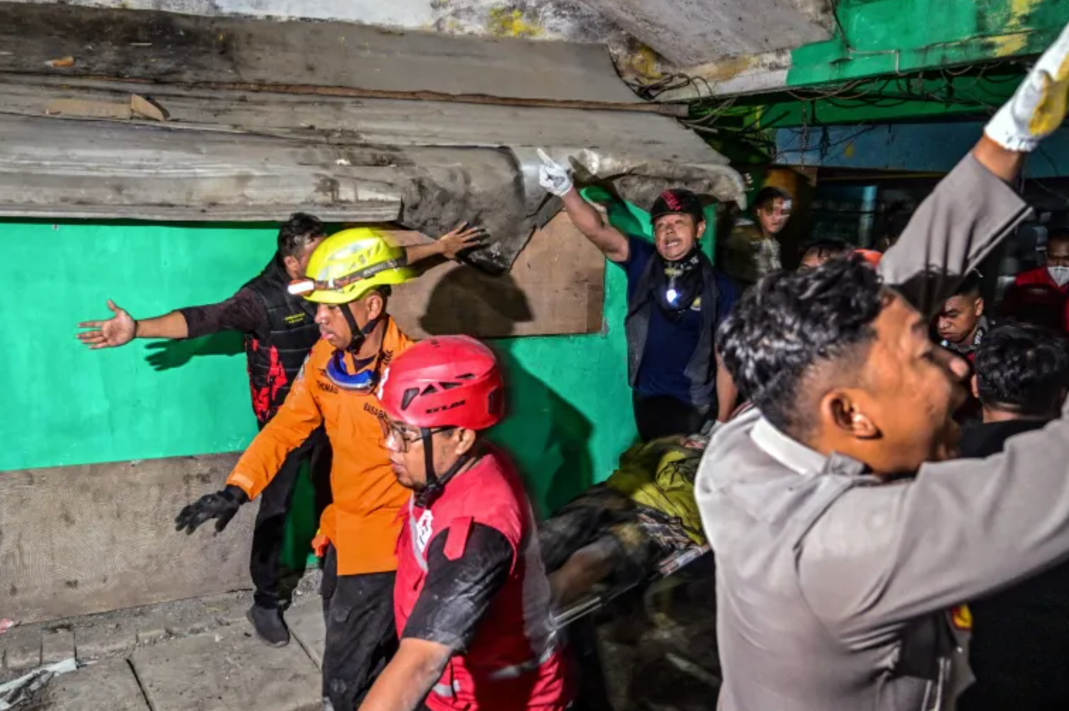 Nhân viên cứu hộ đang khiêng một học sinh bị thương từ phía trong toà nhà đổ sập ra ngoài. (Ảnh: Getty)
