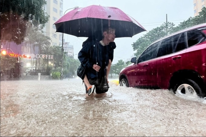 Ông Nguyễn Vân Nga (70 tuổi) đội mưa, cõng cháu khoảng 500 m, từ trường Tiểu học Đại Từ để về chung cư số 1 Nguyễn Cảnh Dị. Ảnh:Huy Mạnh