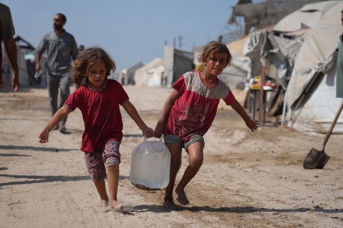 Hai đứa trẻ Palestine xách can nước từ điểm phân phát ở khu lều trại Muwasi, Khan Younis hôm 29/9. Ảnh: AP
