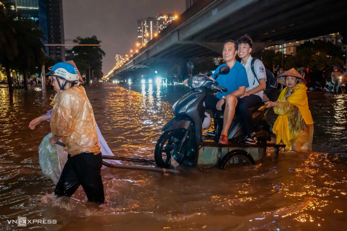 Người dân Hà Nội dùng dịch vụ chở xe máy qua đoạn đường ngập, tối 30/9. Ảnh: Tùng Đinh
