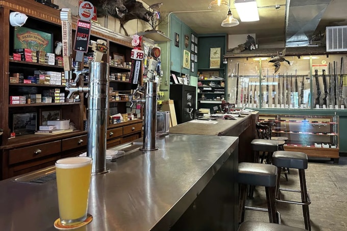 Vòi bia trên quầy bar và tủ trưng bày súng bên trong quán Sportsman. Ảnh: SFG
