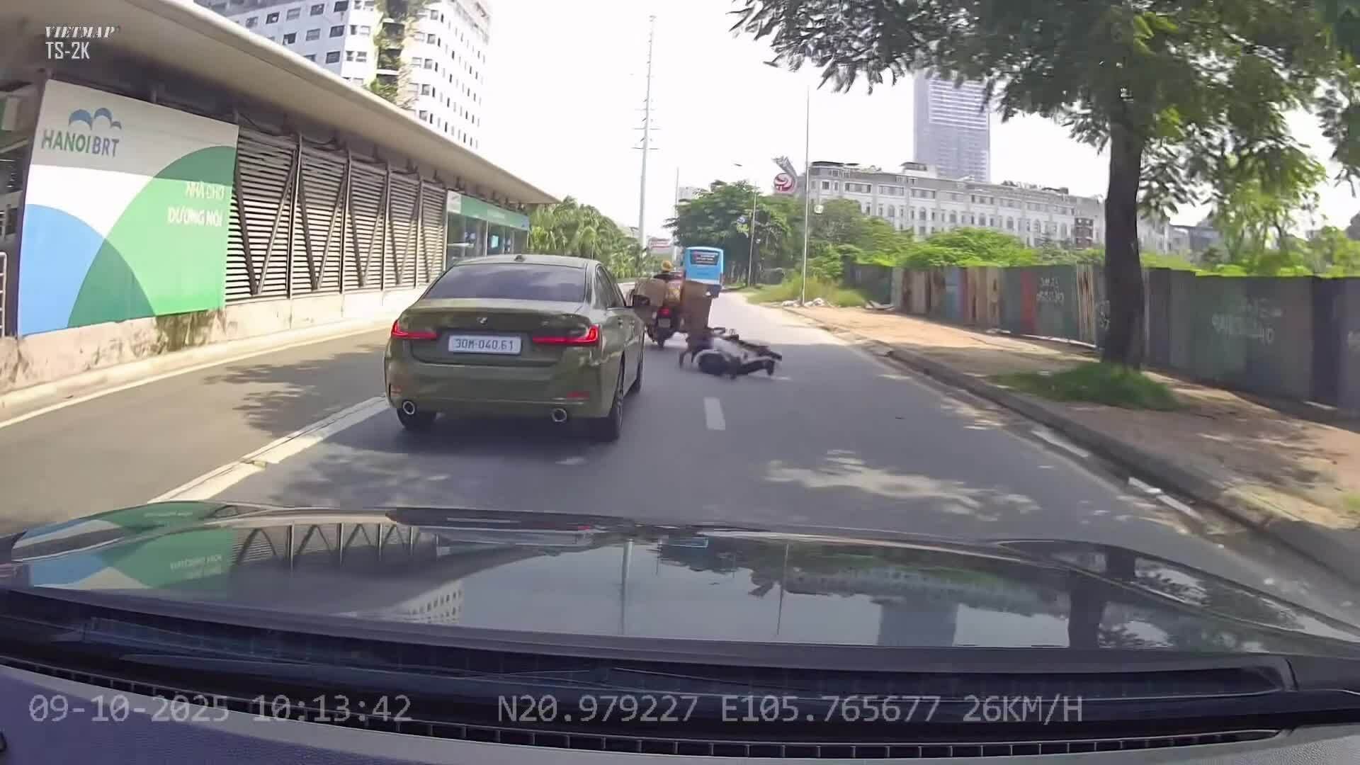 Người đi xe máy huých người đi xe đạp ngã trước đầu ôtô