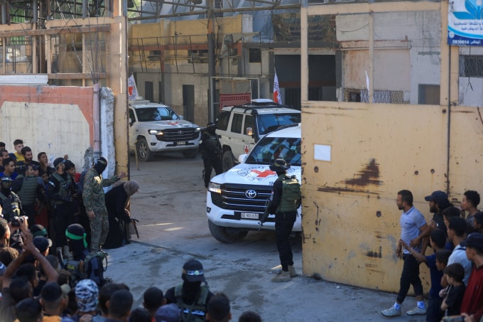 Các chiến binh Hamas đứng quanh xe của Hội Chữ thập đỏ vận chuyển con tin được trao trả ngày 13/10. Ảnh: Reuters