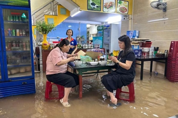 Nước tràn vào quán ăn trên đường Minh Khai. Ảnh: Anh Dũng