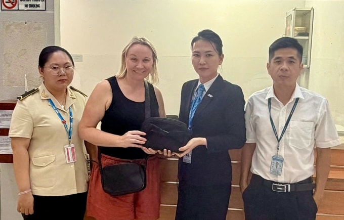 Đại diện Cảng hàng không quốc tế Phú Quốc trao trả túi xách đánh rơi cho du khách người Úc. Ảnh: Dương Đông