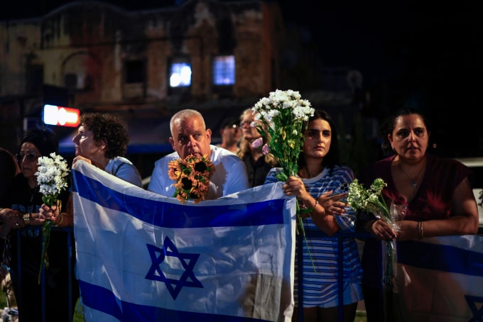 Người dân cầm hoa đón đoàn xe chở thi thể 4 con tin được Hamas bàn giao cho Israel hôm 13/10. Ảnh: AFP