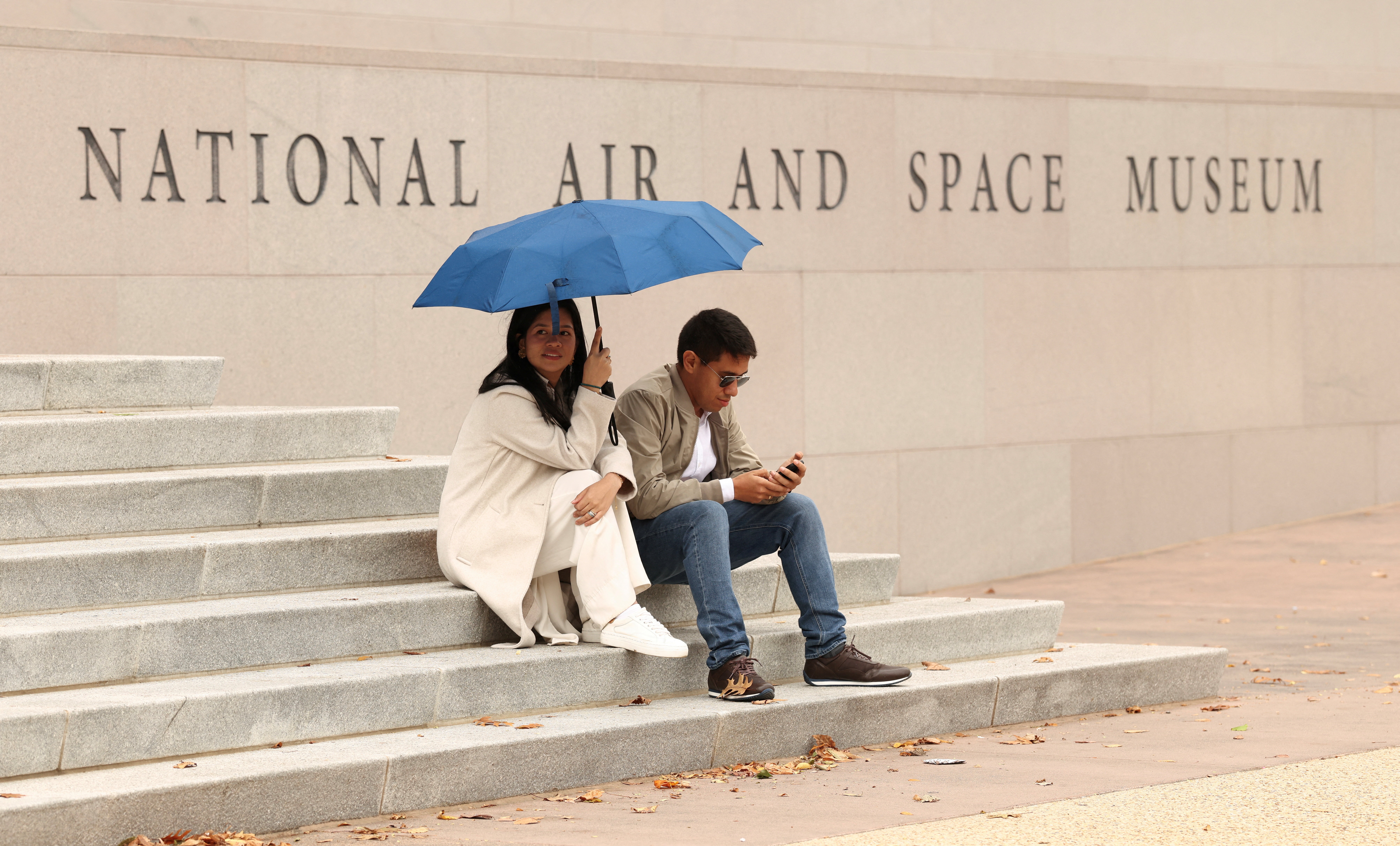 Khách tham quan ngồi trên các bậc thang của Bảo tàng Hàng không và Vũ trụ Quốc gia Smithsonian, nơi đã phải đóng cửa do chính phủ Mỹ ngừng hoạt động. (Ảnh: Reuters)
