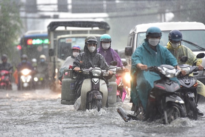 Đi giữa trời mưa, lội nước ngập khiến cơ thể nhiễm lạnh, dễ gây ra ho. Ảnh: Quỳnh Trần