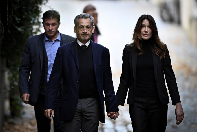 Ông Sarkozy nắm tay vợ, ca sĩ Carla Bruni khi rời nơi cư trú. Ảnh: AFP