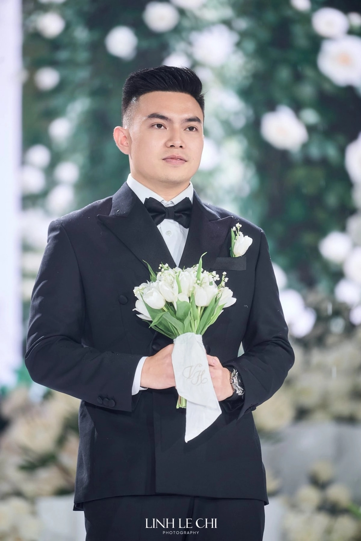 Chú rể Nguyễn Viết Vương xuất hiện với phong thái điềm đạm, tay cầm bó tulip trắng và chiếc khăn thêu lồng hai chữ cái đầu trong tên cô dâu, chú rể.