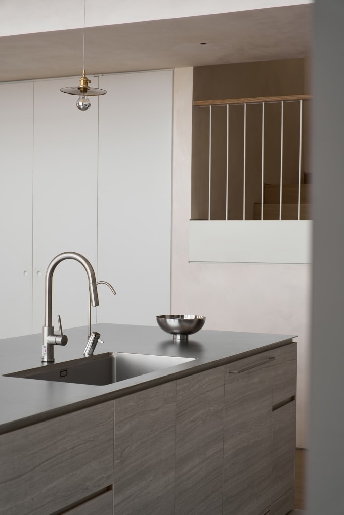 Bề mặt inox phẳng mịn phản chiếu ánh sáng, tạo điểm nhấn sang trọng và dễ bảo trì trong không gian bếp hiện đại. Ảnh: T&PAC Architects