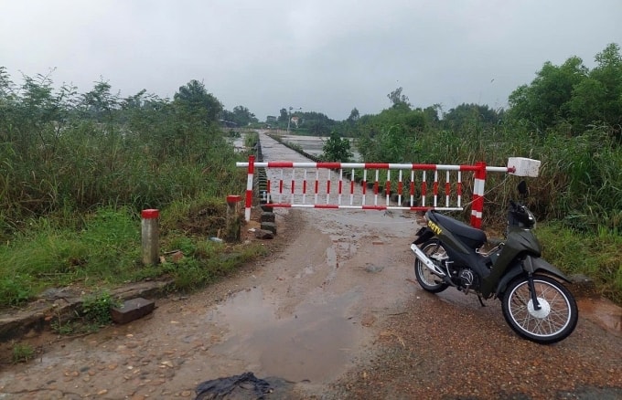 Nước sông tràn qua mặt cầu trên sông Trà Bồng khiến cơ quan chức năng phải đóng barie đầu cầu. Ảnh: Thanh Giang