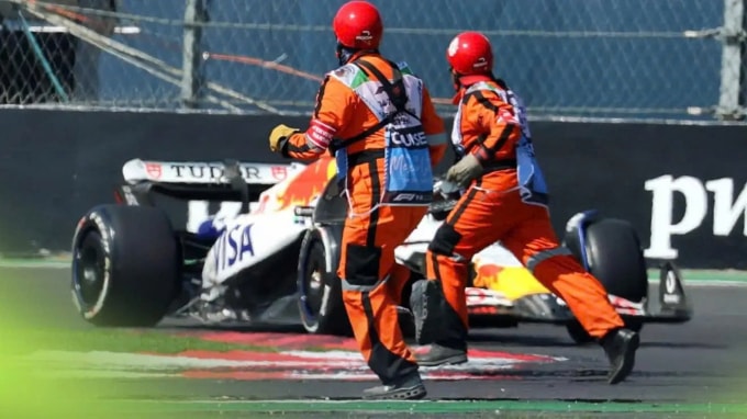 Chiếc xe của Liam Lawson lao tới khi hai nhân viên an ninh băng qua đường đi GP Mexico ngày 26/10/2025. Ảnh: PlanetF1