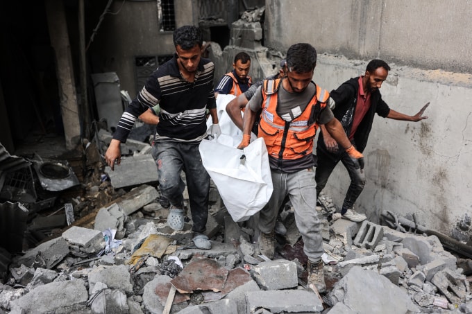 Người dân Palestine di chuyển một thi thể tìm thấy trong đống đổ nát của một ngôi nhà bị trúng đòn không kích trong đêm 28/10 của Israel. Ảnh: AFP