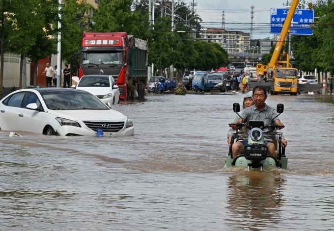 Một người đàn ông lái xe máy qua con phố ngập nước ở quận Mật Vân, ngoại ô Bắc Kinh, tháng 7. Ảnh: Adek Berry/AFP