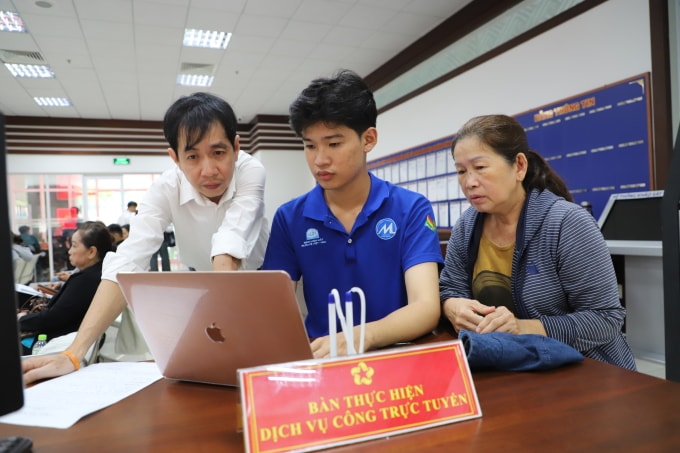 Cán bộ Trung tâm phục vụ hành chính công phường Phú Nhuận, hỗ trợ bà con nhập thông tin lên Cổng dịch vụ công quốc gia. Ảnh: Lê Tuyết