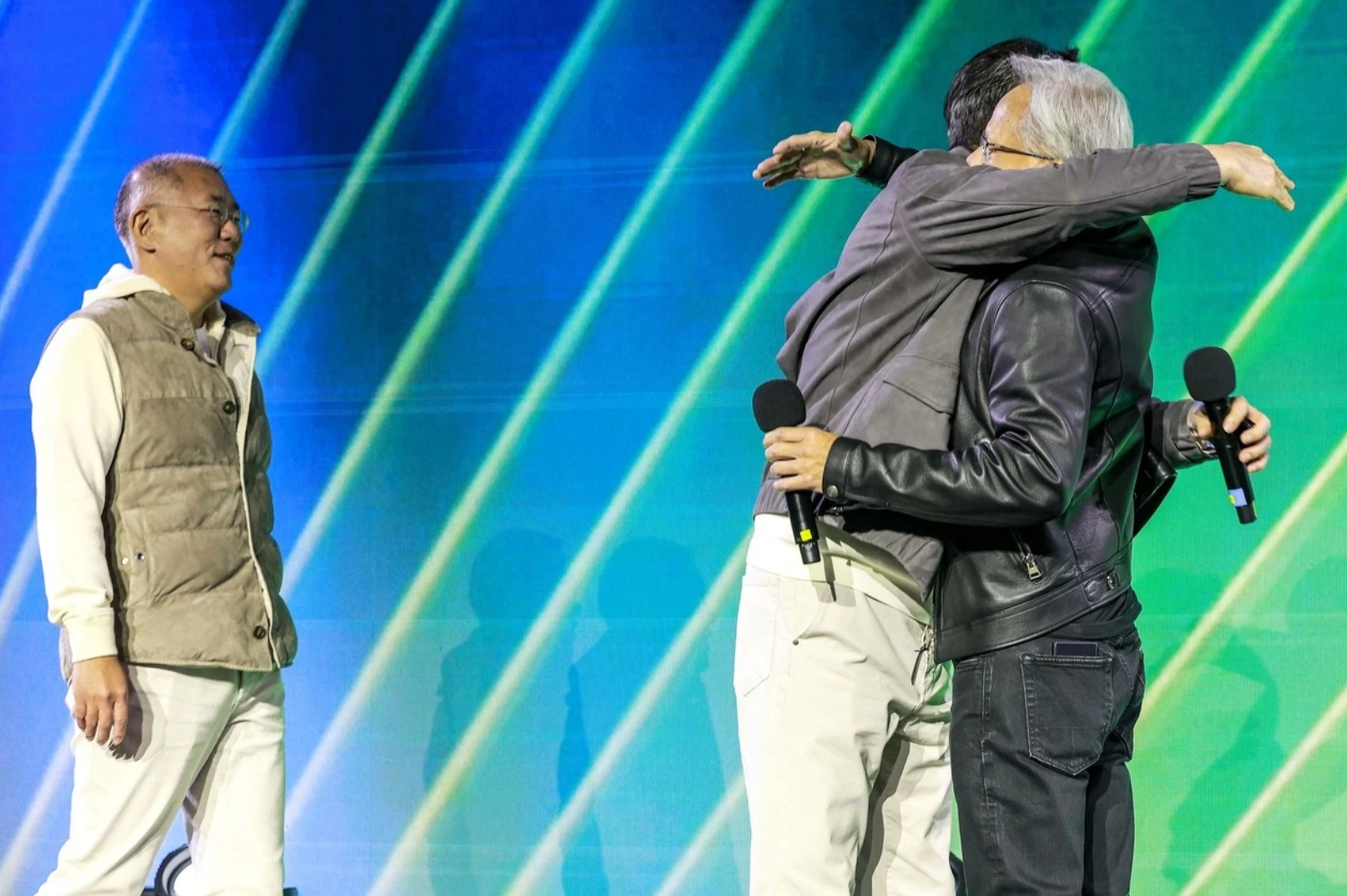 Tổng giám đốc điều hành Nvidia Jensen Huang (phải) ôm Chủ tịch Samsung Electronics Lee Jae-yong, trong khi Chủ tịch điều hành Hyundai Motor Group Chung Euisun (trái) đứng quan sát tại sự kiện kỷ niệm 25 năm ra mắt card đồ họa GeForce của Nvidia ở Coex ở Seoul.
