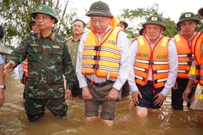 Tổng Bí thư cùng đoàn công tác lội nước vào thăm người dân vùng lũ. Ảnh: Vạn An