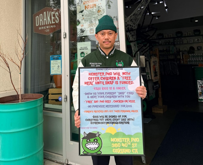 Tran Huu Thuyen giơ bảng hiệu cung cấp phở miễn phí cho trẻ em trước nhà hàng Monster Pho ở Oakland, California. Ảnh: Tee Tran