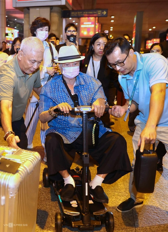 Tài tử Hồng Kim Bảo ngồi xe lăn và được các vệ sĩ hỗ trợ khi xuất hiện ở sân bay Tân Sơn Nhất. Ảnh: Quỳnh Trần