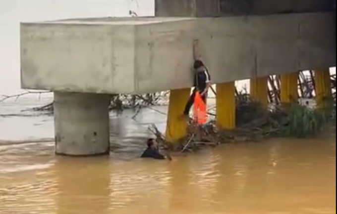 Anh Trần Hàng nhảy xuống trụ cầu Cầu Lâu, phường Điện Bàn sau dùng dây thừng đu xuống dưới cứu người mắc kẹt trong nước lũ, trưa 5/11. Ảnh: Hà Trương