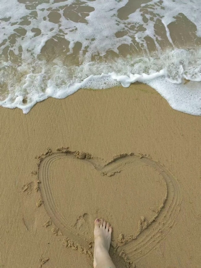 Tháng 7/2023, Ngô Lệ vẽ trái tim trên bãi biển Uy Hải khi đi gặp bạn trai qua mạng. Ảnh: Beijing News