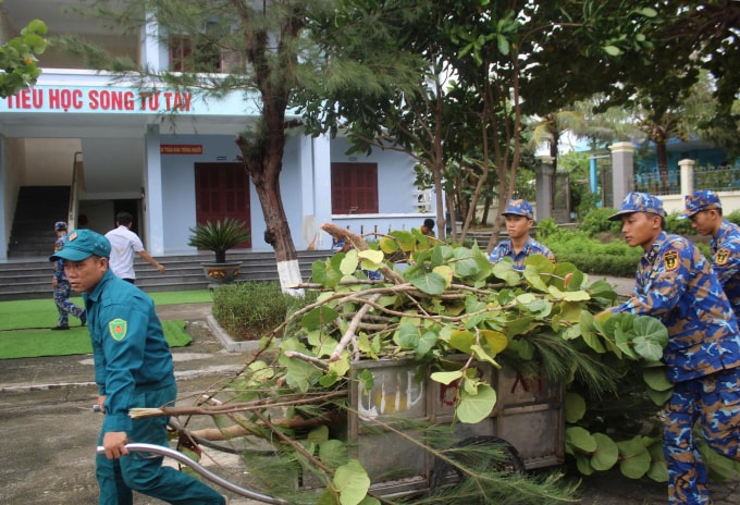 Cán bộ, chiến sĩ Đặc khu Trường Sa thu dọn cây cối bị gãy sau bão. Ảnh: Hoa Ngọc Ánh