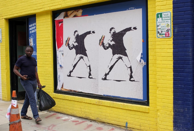 Hình ảnh một người biểu tình ném bánh mỳ kẹp được dán ở một khu phố thủ đô Washington, Mỹ ngày 21/8. Ảnh: AFP