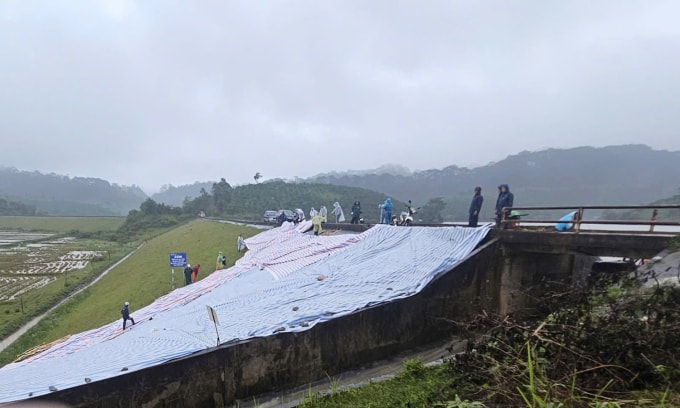 Chính quyền trải bạt thân đập nhằm hạn chế đất bị xói lở khi mưa lớn. Ảnh: Khánh Hương