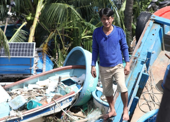 Anh Châu đứng trên tàu bị lật nghiêng mắc kẹt giữa những chiếc khác ở trong gần bờ. Ảnh: Đình Văn