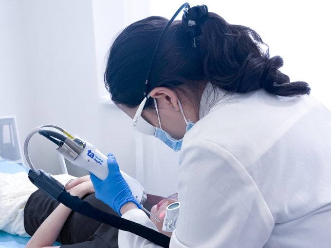 Bác sĩ Trang sử dụng laser Nd:YAG xung dài giảm mụn viêm và hồng ban sau mụn cho chị Hằng. Ảnh: Bệnh viện Đa khoa Tâm Anh