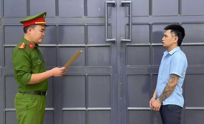 Nghi can Đạt (góc phải) nghe cảnh sát đọc lệnh bắt. Ảnh: Công an cung cấp