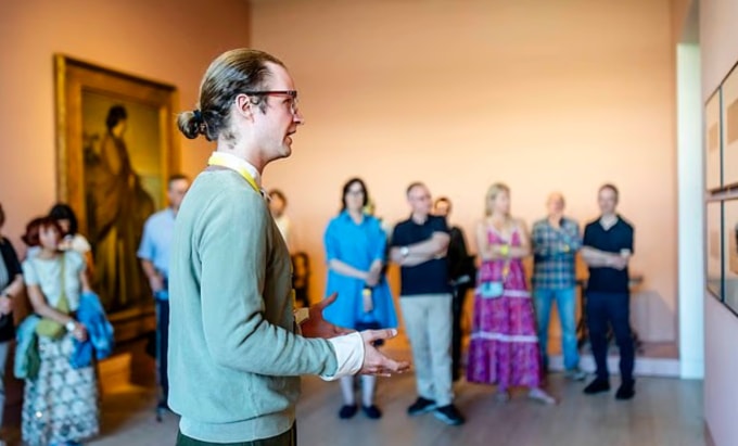 Hướng dẫn viên cáu kỉnh Joseph Langelinck, do nghệ sĩ Carl Brandi thủ vai, đang thuyết minh cho khách tham quan bảo tàng. Ảnh: