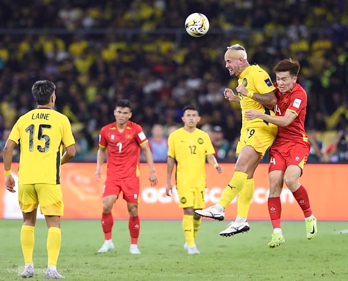 Nguyễn Hoàng Đức (áo đỏ phải) tranh chấp với tiền đạo Malaysia gốc Argentina Rodrigo Holgado trong trận Việt Nam thua Malaysia 0-4 ở lượt hai bảng F vòng loại cuối Asian Cup 2027, trên sân Bukit Jalil, Malaysia ngày 10/6/2025. Ảnh: Hai Tư