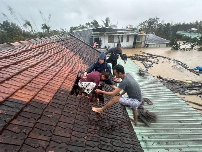 Người dân Quy Nhơn được đội cứu hộ dỡ mái nhà cứu ra ngoài, sáng 19/11. Ảnh: Lương Vĩnh Long Nhật