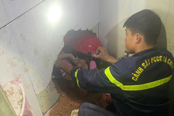 Cảnh sát đục tường tiếp cận đưa bé gái khỏi đống đất đá. Ảnh: Lê Tiến