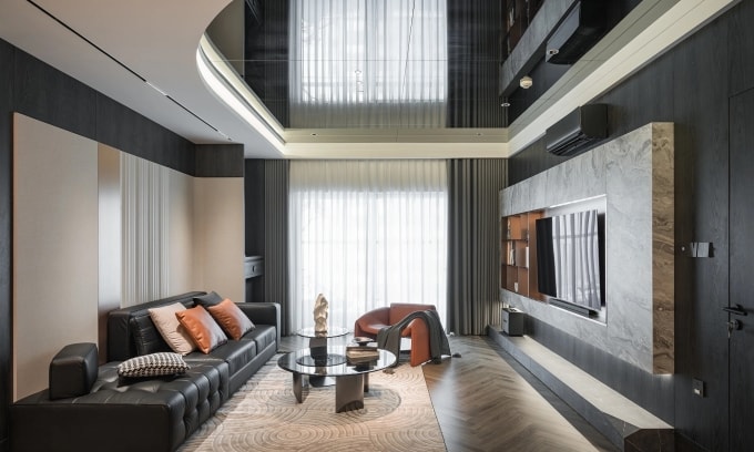 Không gian phòng khách sử dụng tông trầm đen làm nền, kết hợp điểm nhấn cam đất và chất liệu kim loại, da, đá vân giúp tăng chiều sâu, tạo cảm giác sang trọng mà vẫn giữ được sự ấm cúng và cân bằng thị giác. Ảnh: KLUX