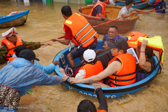 Các đội cứu hộ phường Tây Nha Trang dùng thuyền thúng chở người, tài sản đến nơi an toàn. Nước lũ chảy xiết trên đường khiến việc cứu hộ gặp khó khăn. Ảnh: Bùi Toàn