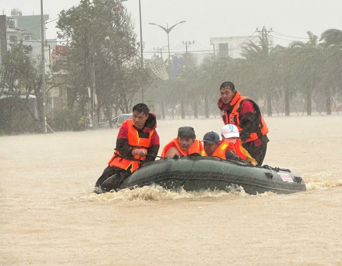 Các thành viên trong đội cứu hộ SOS 38 Hà Tĩnh di chuyển người dân bị cô lập trong nước lũ tại phường Quy Nhơn Bắc đến nơi an toàn, ngày 19/11. Ảnh: Lương Vĩnh Long Nhật