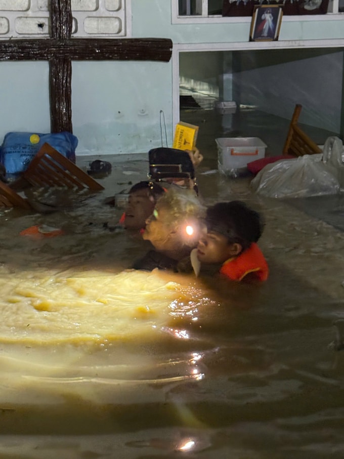 Long Nhật (đeo đèn pin) đưa cụ bà ngoài 70 tuổi ở phường Quy Nhơn Bắc, Gia Lai đến nơi an toàn, ngày 19/11. Ảnh: Lương Vĩnh Long Nhật