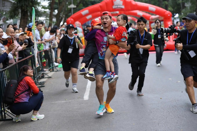 Nghệ sĩ Xuân Bắc bế VĐV nhí về đích ở Kun Marathon Hà Nội 2024. Ảnh: VnExpress Marathon