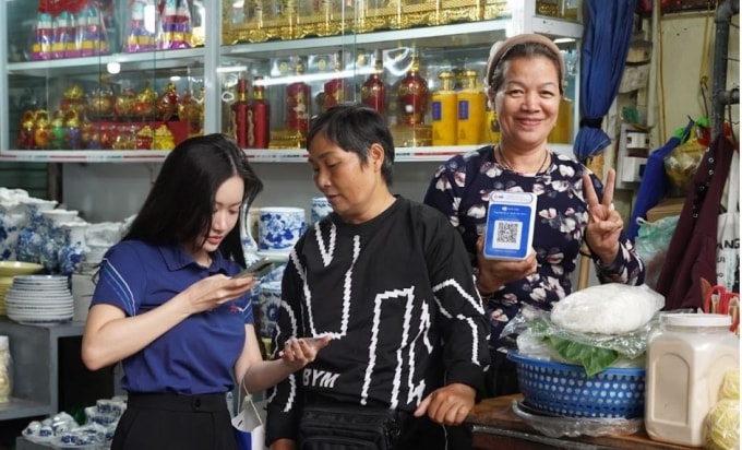 Nhân viên MB hướng dẫn tiểu thương chợ Hôm về tính năng hóa đơn điện tử. Ảnh: MB