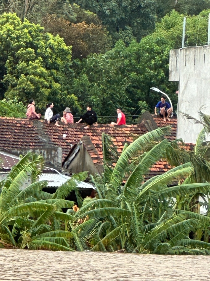 Người dân ở Tuy Hòa, Đăk Lăk trèo lên mái nhà ngồi khi nước lũ dâng cao, nhấn chìm toàn bộ tầng một, chiều 21/11. Ảnh: Lương Vĩnh Long Nhật