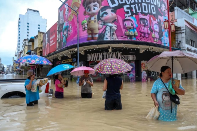 Người dân và du khách di chuyển trong nước vì lũ lụt tại huyên Hat Yai hôm 23/11. Ảnh: Reuters