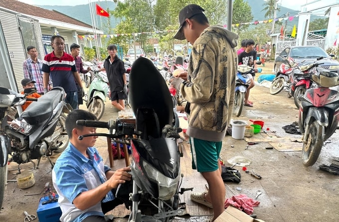 Anh Đức (áo xanh) cùng cả nhóm sửa xe cho người dân thôn Mỹ Điền, Hòa Thịnh, sáng 26/11. Ảnh nhân vật cung cấp